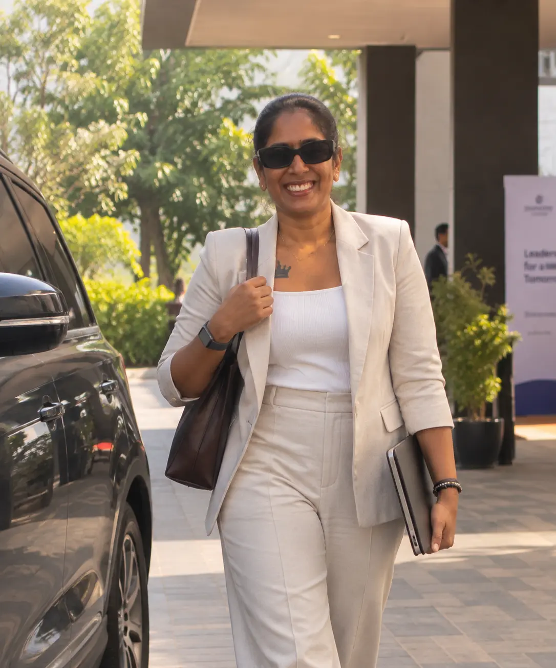 Dr. Indhu Nagaiah in a cream suit, smiling as she arrives at an event venue
